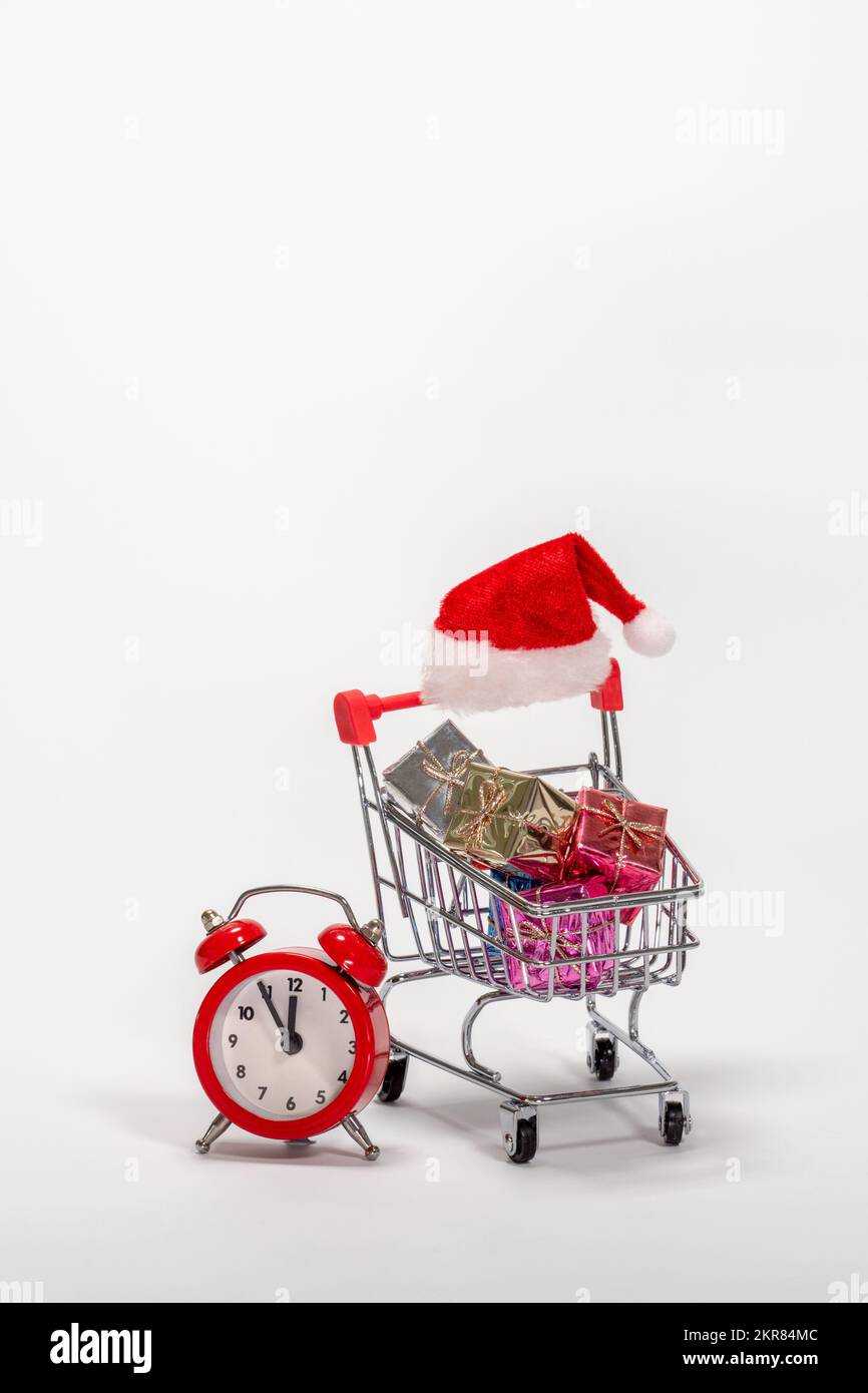 Un chariot rempli de cadeaux de Noël de dernière minute et un réveil rouge. Banque D'Images