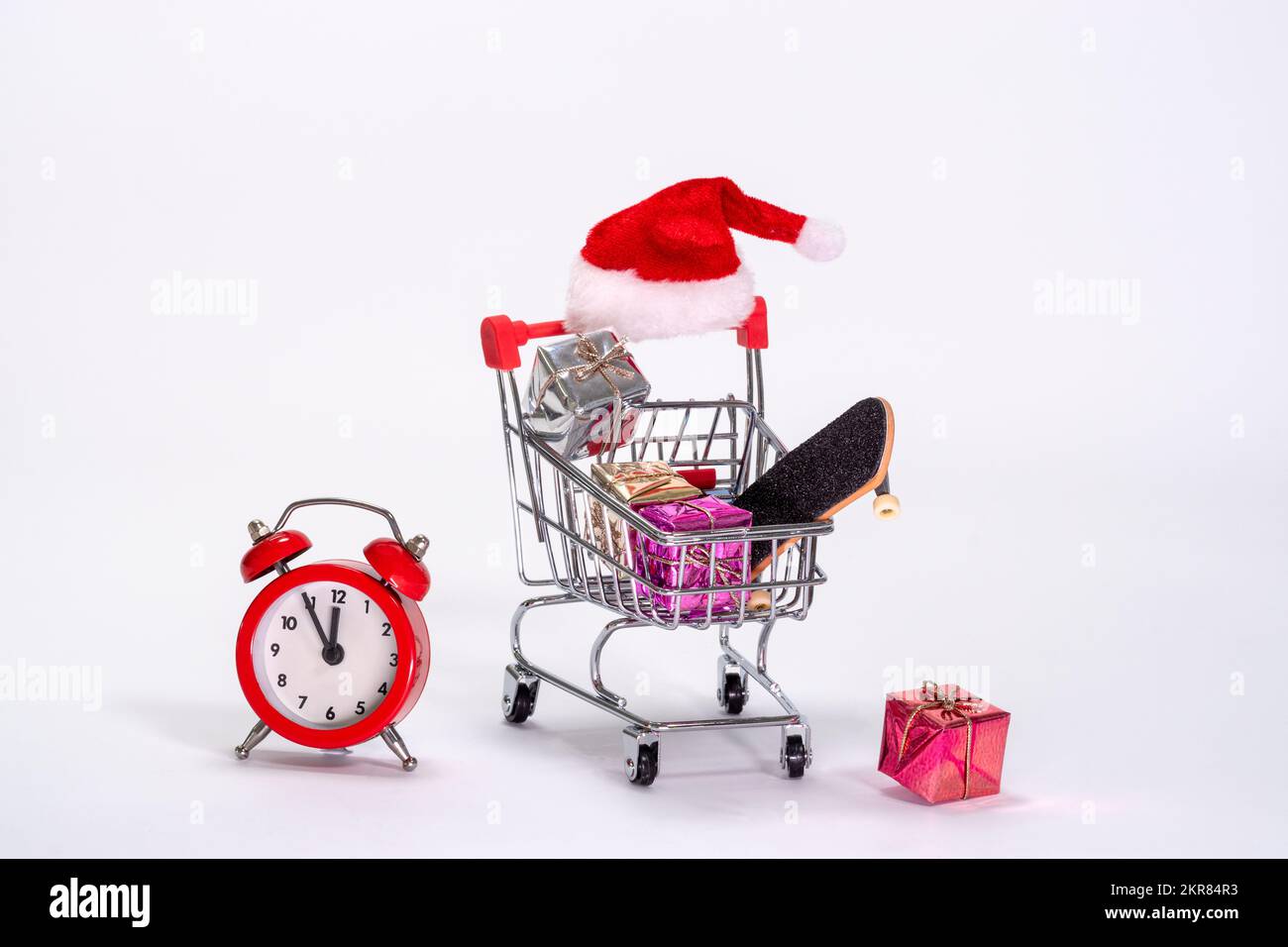 Un chariot rempli de cadeaux de dernière minute et un réveil rouge montrant la pression du temps à Noël. Banque D'Images