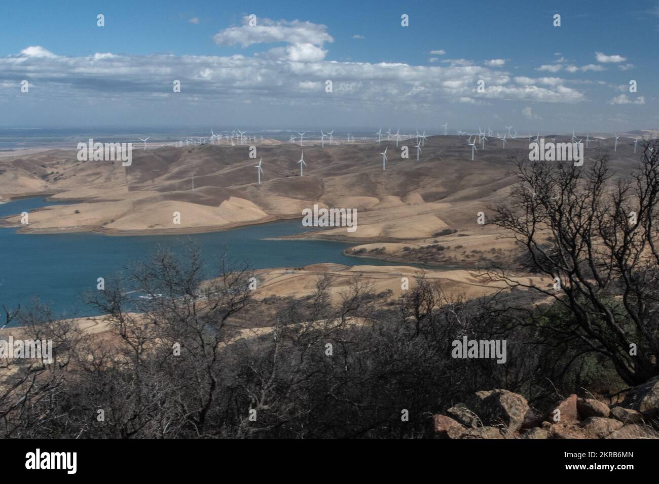 Vue sur le réservoir de Los Vaqueros et les collines parsemées d'éoliennes en Californie, aux États-Unis. Banque D'Images