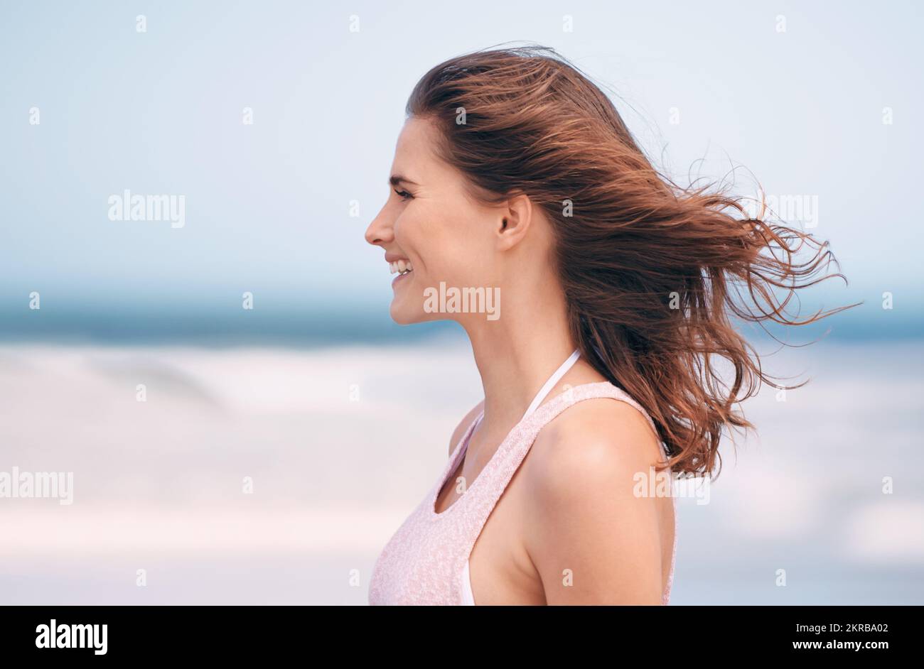 J'adore la brise fraîche. une femme attrayante appréciant une journée à la plage. Banque D'Images