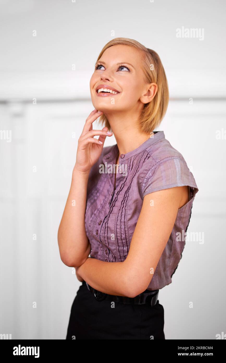 Se demander ce que l'avenir réserve. une belle jeune femme souriante habillée pour le bureau. Banque D'Images