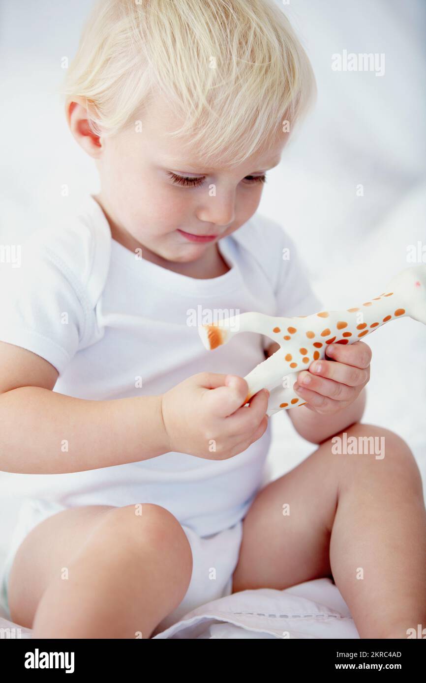 Apprendre sur les animaux. un jeune bébé jouant avec une girafe jouet. Banque D'Images