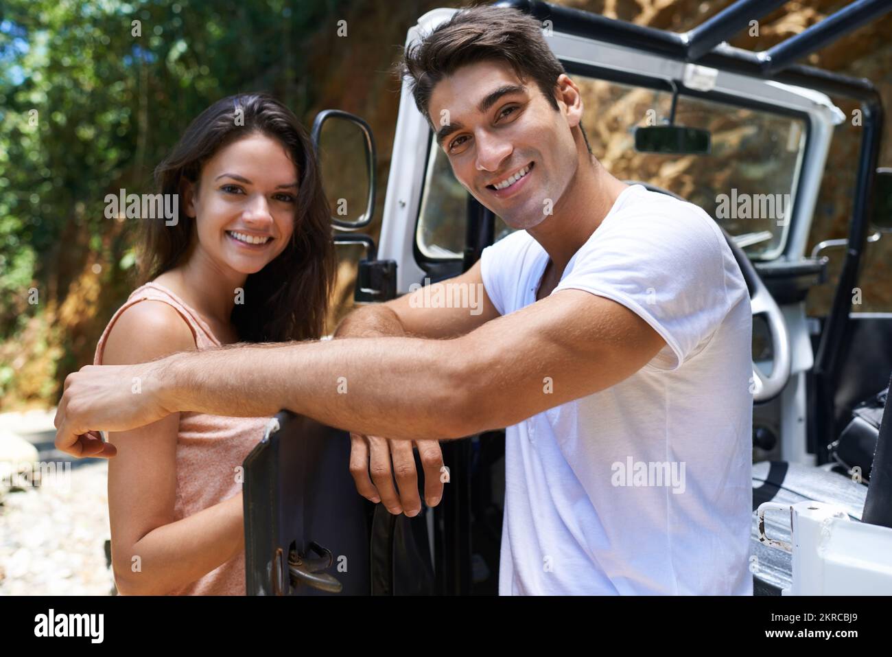 Quatre roues motrices - la seule façon de procéder. Portrait d'un jeune couple penché contre la porte ouverte d'un 4x4. Banque D'Images