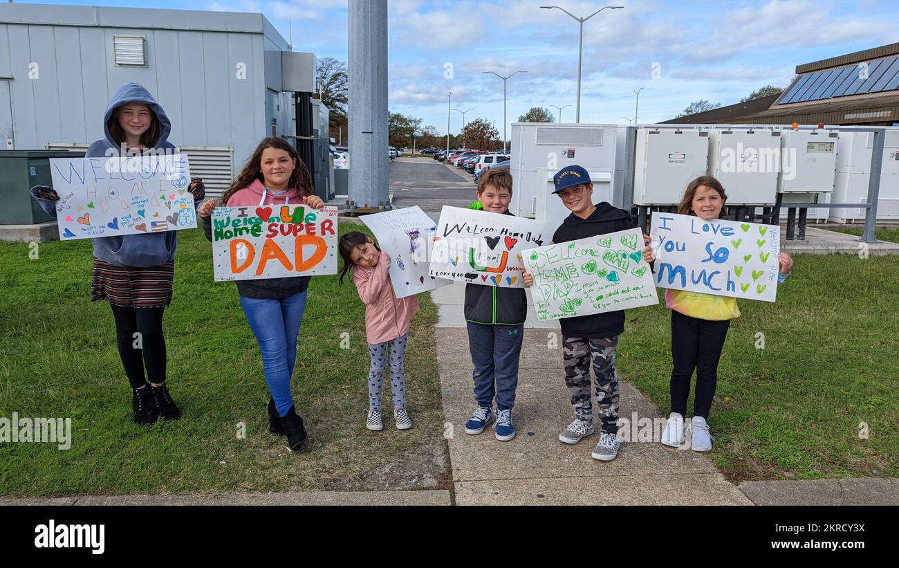 Une famille USCGC Northland (WMEC 904) pose avec des signes de bienvenue à la maison au retour du Cutter à homeport à Portsmouth, en Virginie, le 14 novembre 2022. En cours, Northland a mené des missions d'interdiction des migrants, d'application de la loi et des missions humanitaires. Banque D'Images