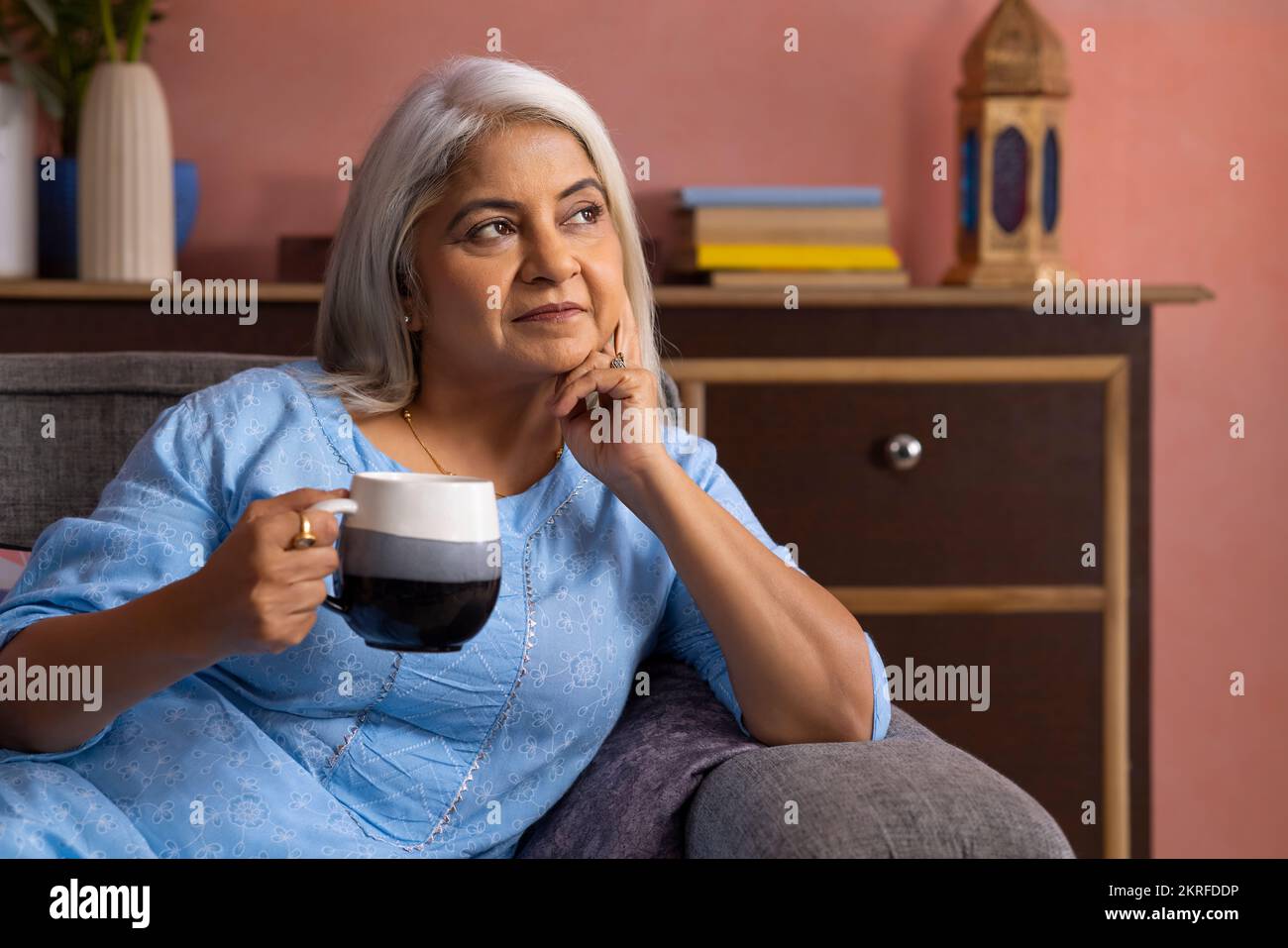 Portrait d'une vieille femme attentionnés qui regarde loin avec une tasse de thé à la main Banque D'Images
