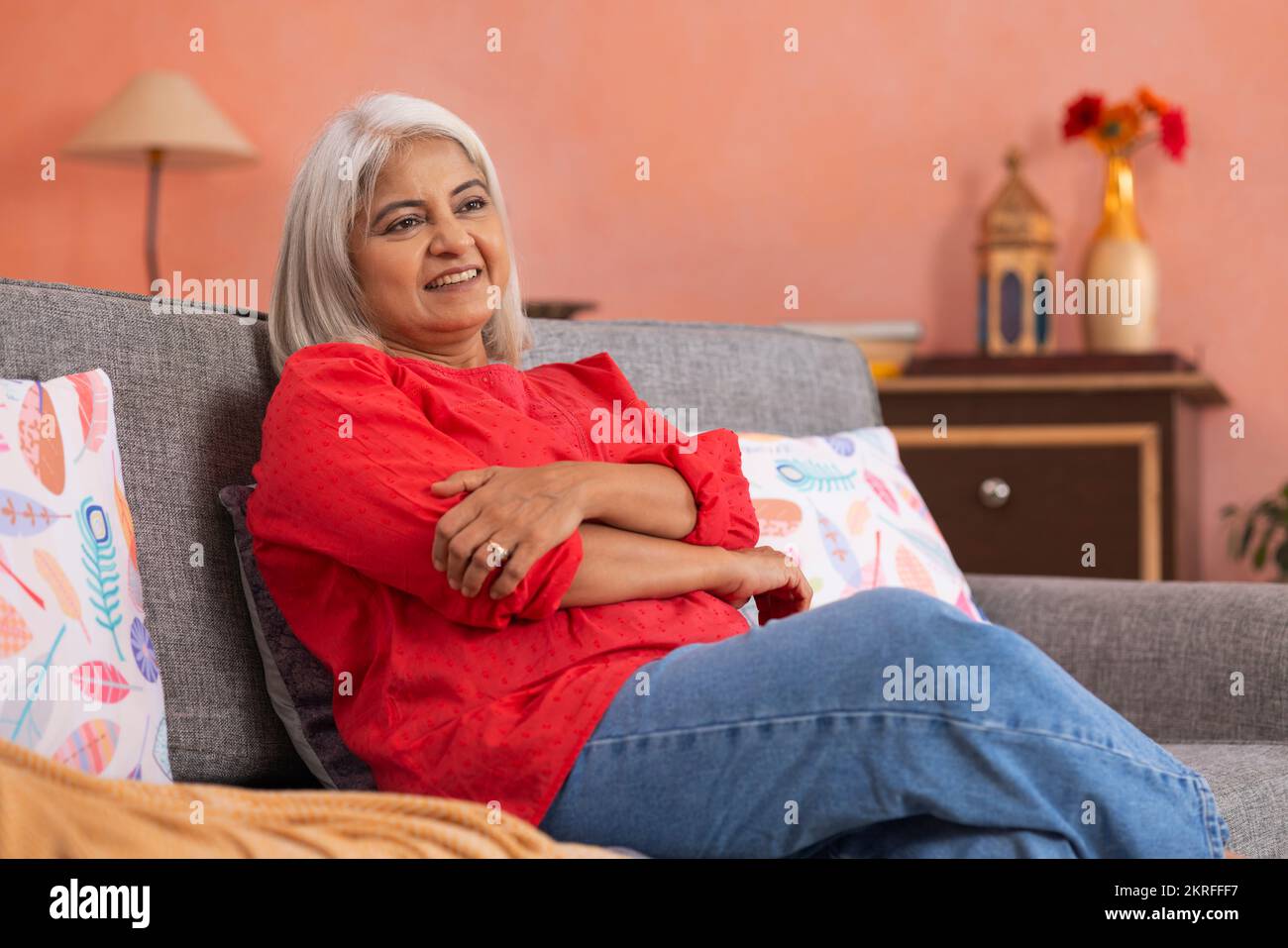 Portrait d'une vieille femme se reposant sur un canapé dans la salle de séjour Banque D'Images