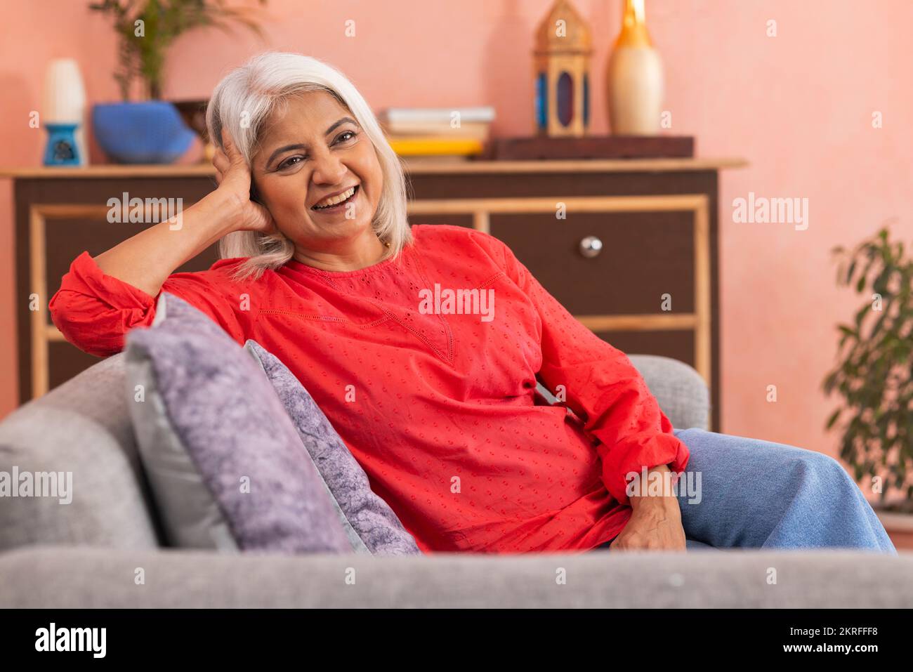 Portrait d'une vieille femme joyeuse se relaxant sur un canapé dans le salon Banque D'Images