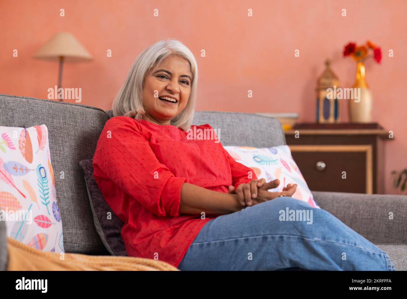 Portrait d'une vieille femme se reposant sur un canapé dans la salle de séjour Banque D'Images