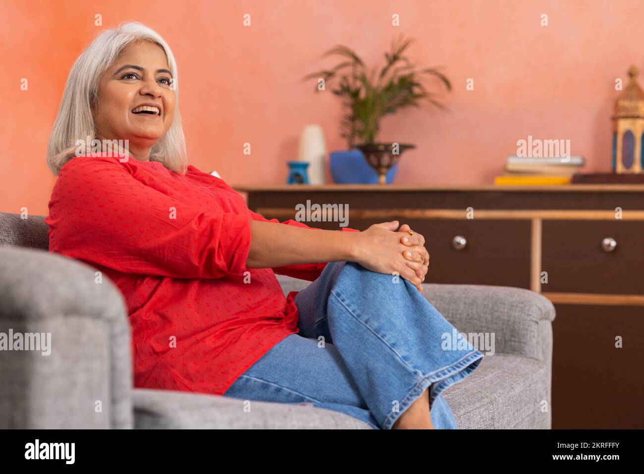 Portrait d'une vieille femme se reposant sur un canapé dans la salle de séjour Banque D'Images