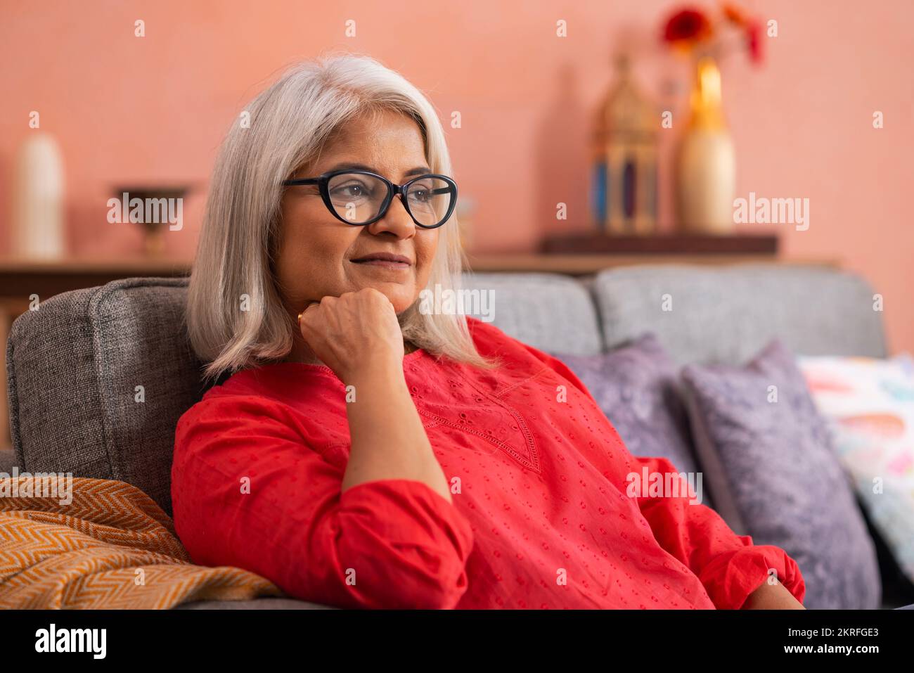 Portrait d'une vieille femme se reposant sur un canapé dans la salle de séjour Banque D'Images
