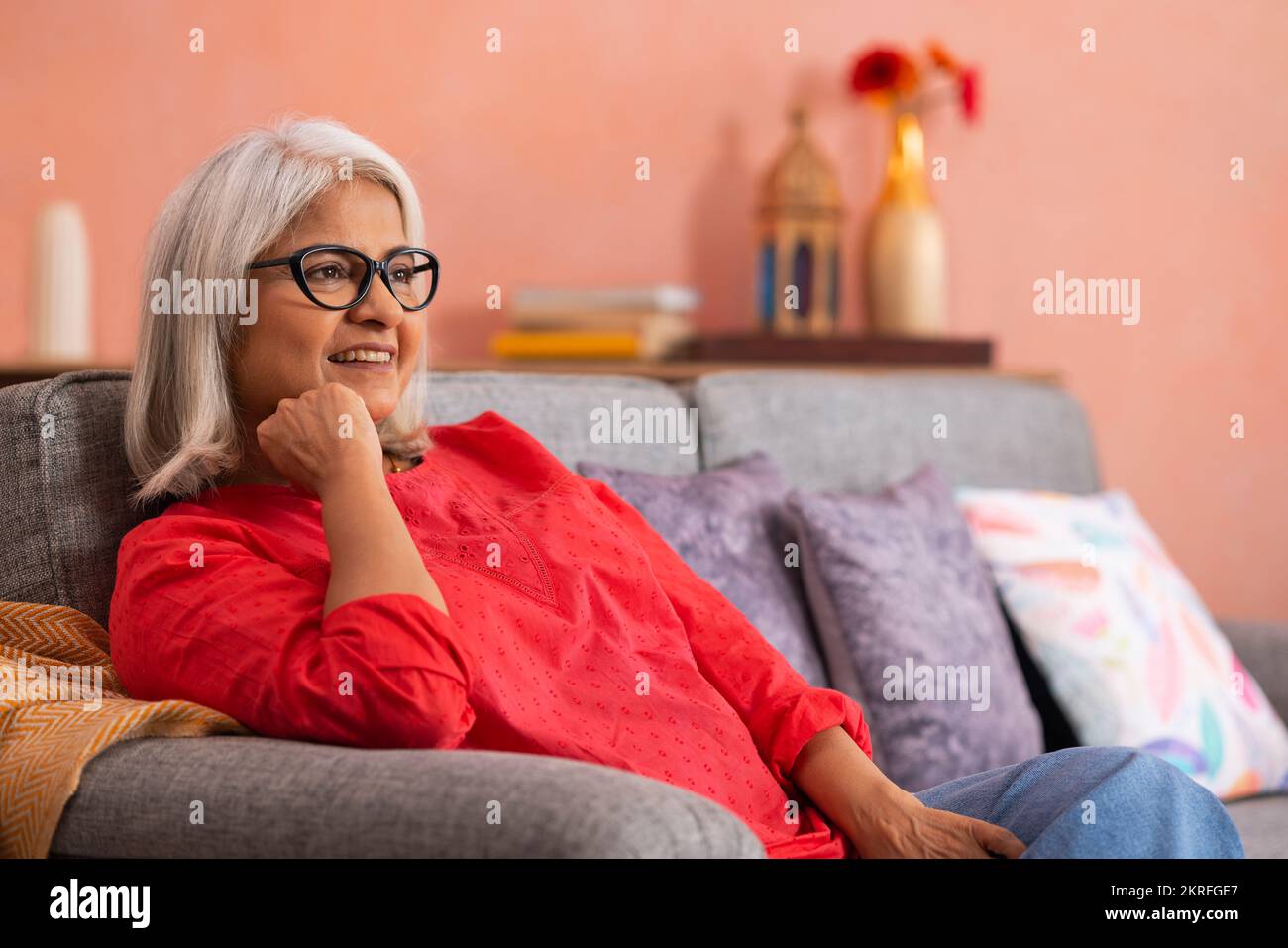 Portrait d'une vieille femme se reposant sur un canapé dans la salle de séjour Banque D'Images