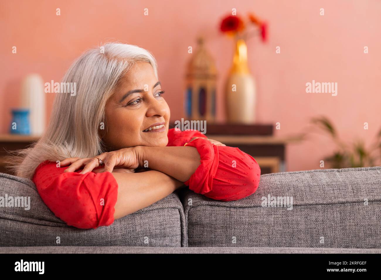 Portrait d'une vieille femme penchée sur un canapé et regardant loin Banque D'Images