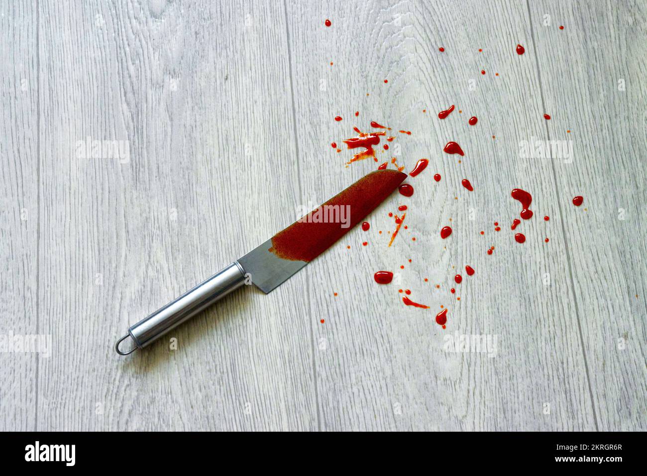 Un couteau avec une éclaboussure de sang se trouve sur le linoléum, en gros plan. Concept de crime, vol qualifié et vol, agression Banque D'Images