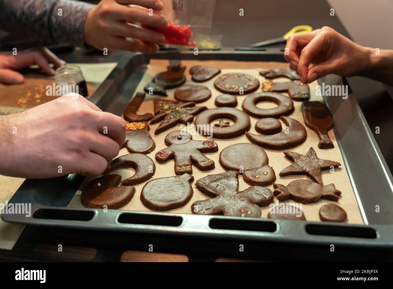 Un groupe d'amis se sont réunis dans la soirée et passent du temps ensemble à cuisiner des biscuits au pain d'épice. Banque D'Images