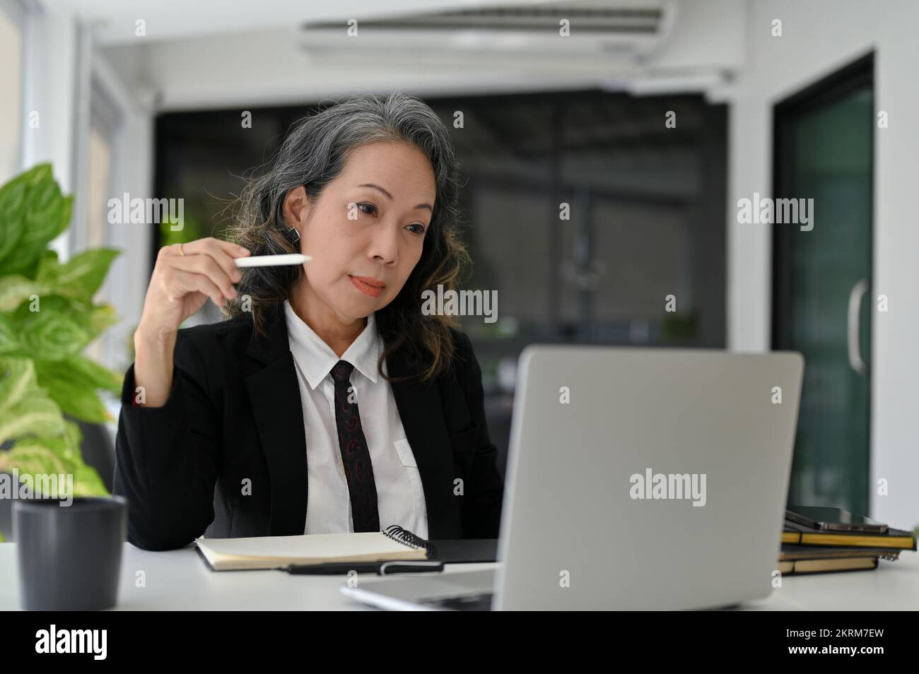 Professionnelle et intelligente femme d'affaires asiatique senior se concentrant sur sa tâche professionnelle sur l'écran d'ordinateur portable, travaillant dans son bureau. Banque D'Images