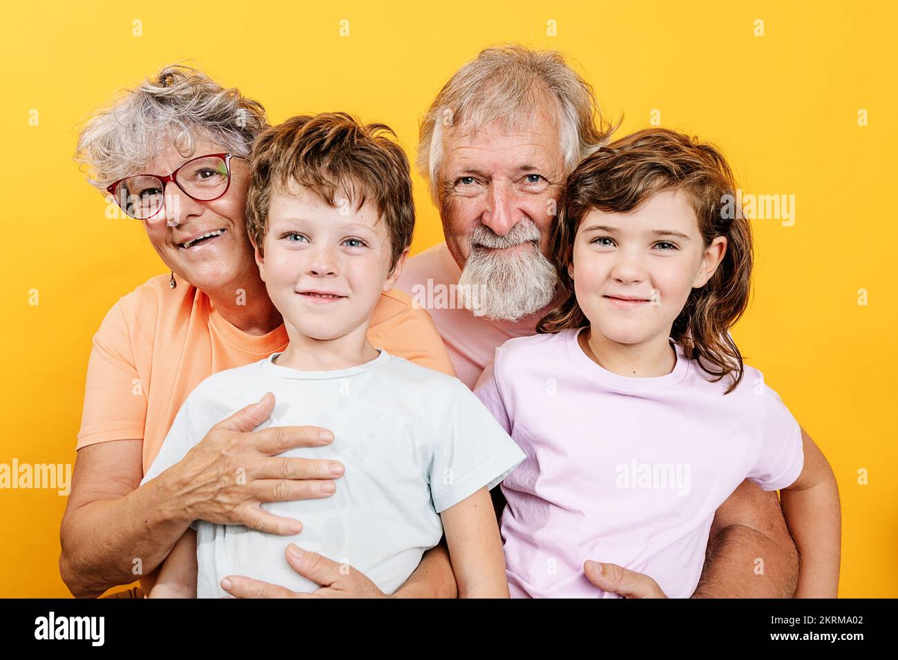 Grands-parents gaies embrassant des petits-enfants portant des tenues décontractées regardant l'appareil-photo s'amuser ensemble Banque D'Images
