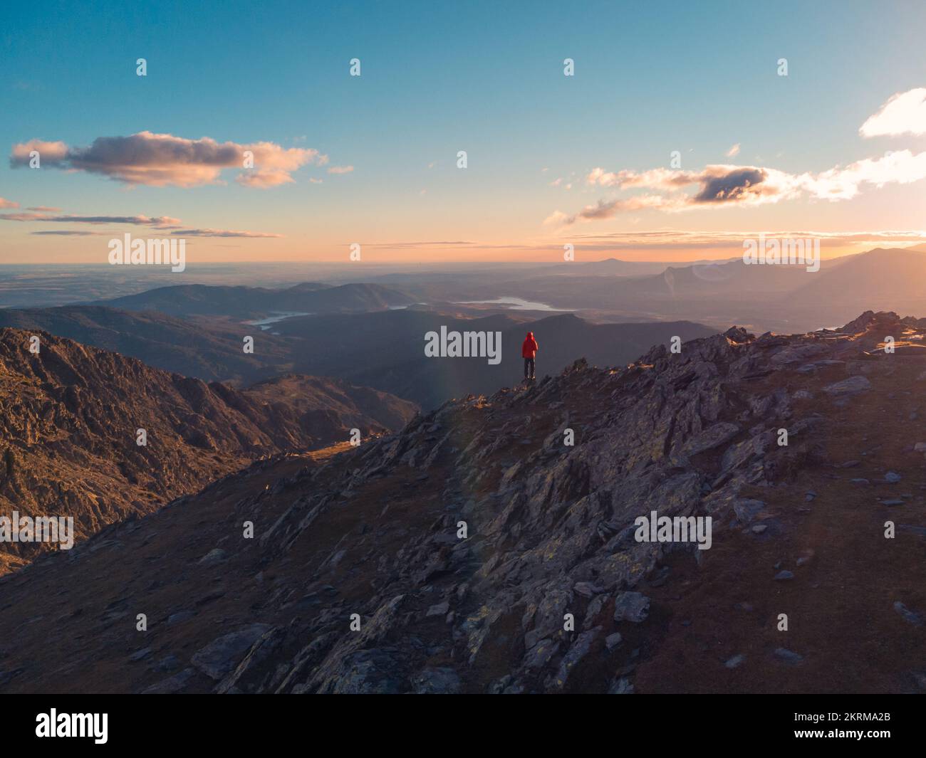 Solitaire de loin touristique dans le paysage majestueux avec la crête de la Sierra Norte traversant la vallée sous ciel clair avec des nuages au coucher du soleil, Espagne Banque D'Images