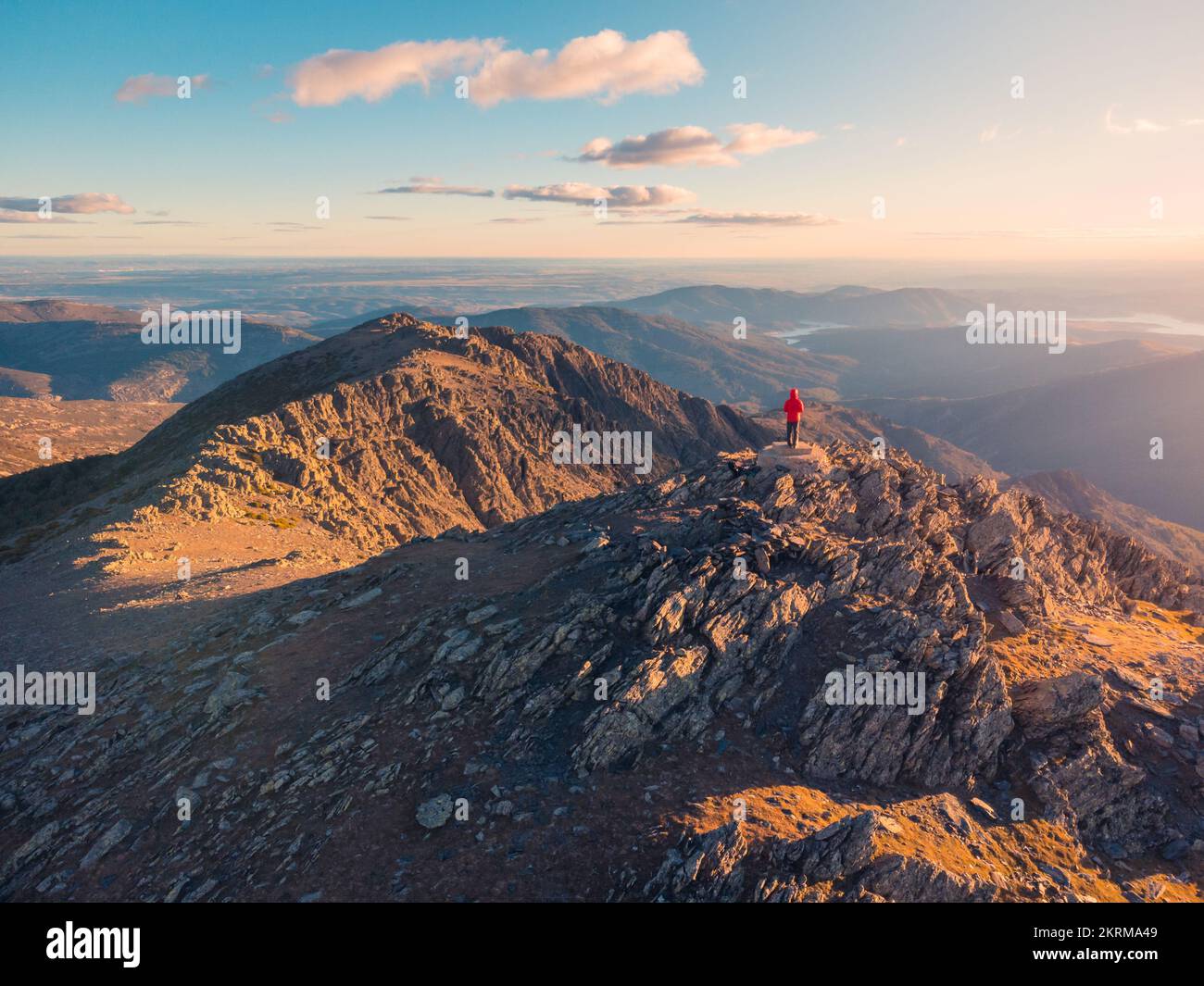 Solitaire de loin touristique dans le paysage majestueux avec la crête de la Sierra Norte traversant la vallée sous ciel clair avec des nuages au coucher du soleil, Espagne Banque D'Images