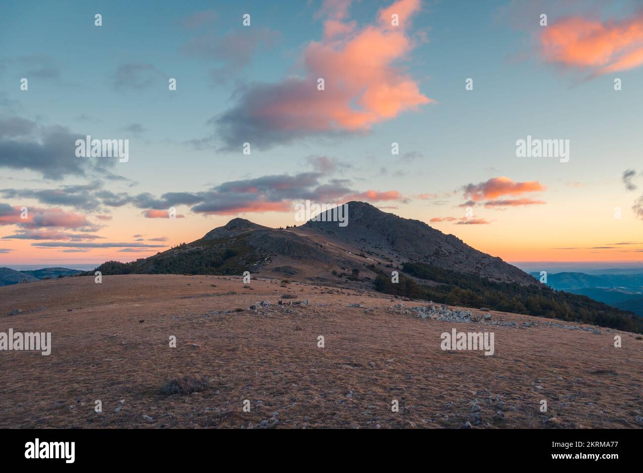 Vaste terrain au sommet de la crête de montagne dans la vallée sous ciel bleu avec des nuages au coucher du soleil, Sierra Norte Banque D'Images