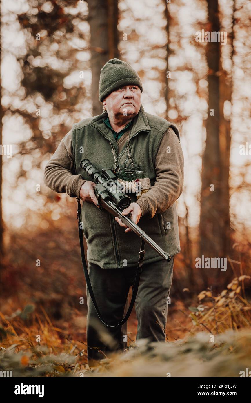 Saison de chasse d'automne, chasseur avec carabine à la recherche d'animaux sauvages dans le bois ou la forêt, concept de sports de plein air Banque D'Images