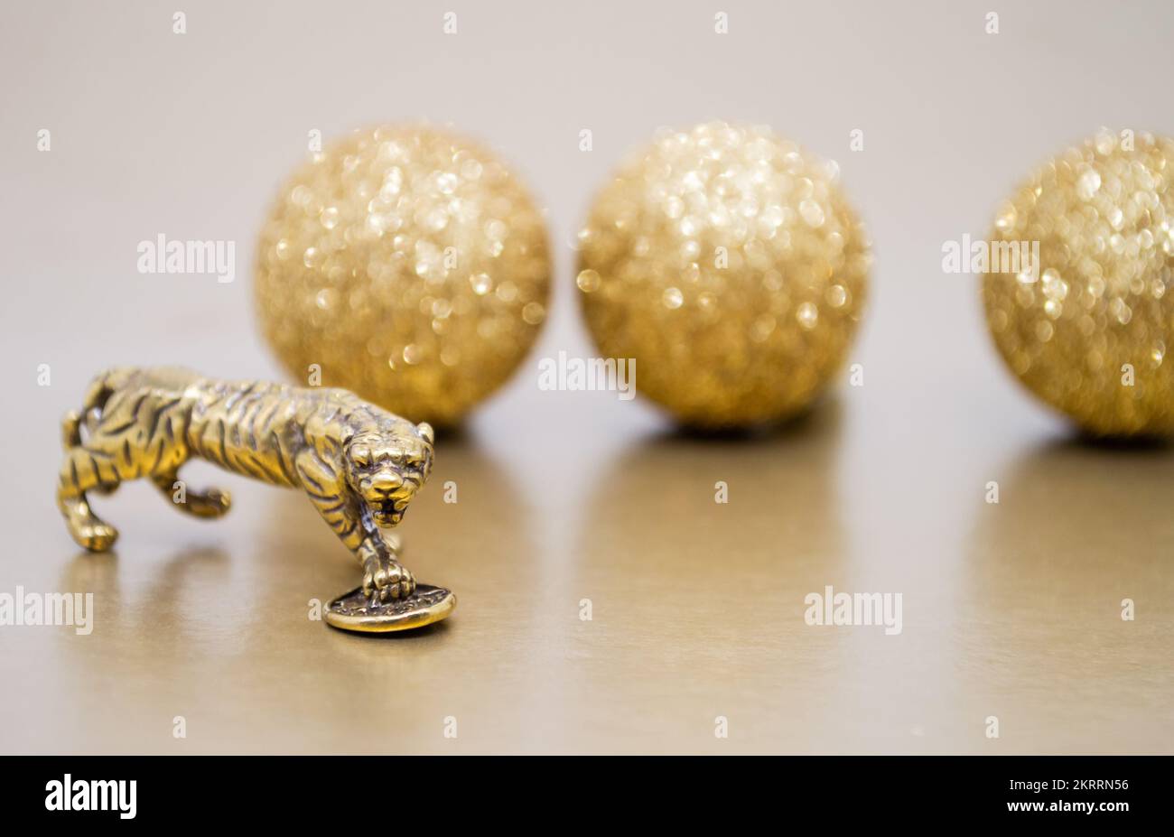 Une figure en bronze d'un tigre avec une pièce sur un fond avec des boules brillantes dorées, espace de copie. Souhaits de pouvoir, de bien-être financier et de richesse. Banque D'Images