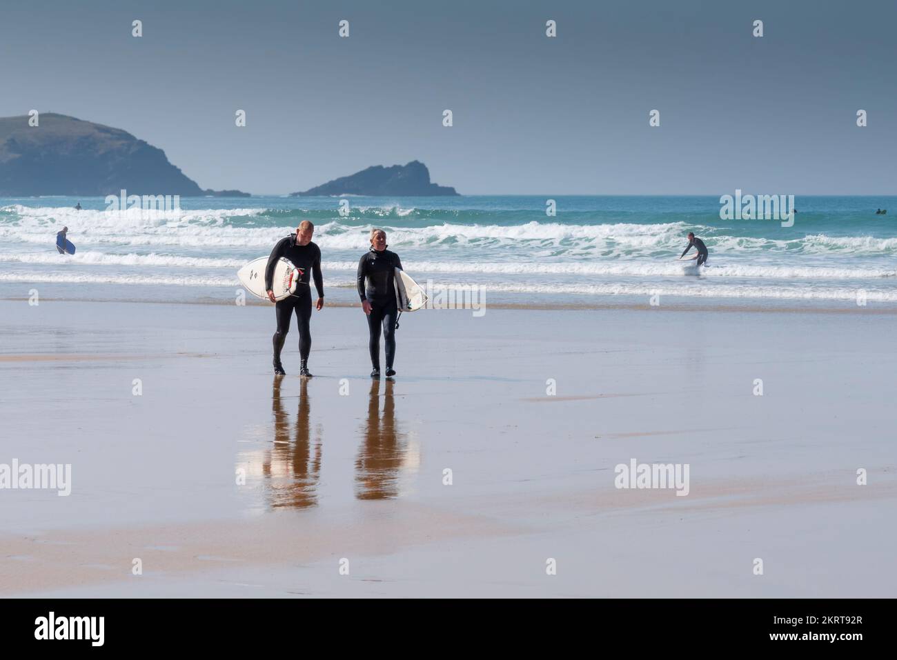 Deux surfeurs matures marchant sur la plage après une séance de surf à Fistral à Newquay, en Cornouailles, au Royaume-Uni. Banque D'Images