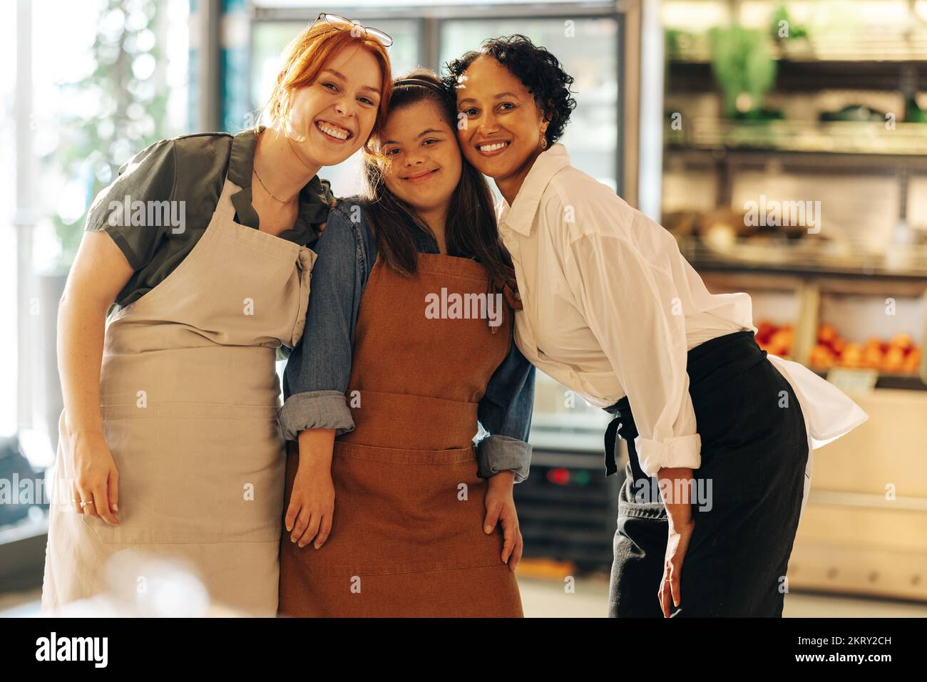 Divers travailleurs de la vente au détail souriant à la caméra tout en se tenant ensemble dans une épicerie. Groupe de trois femmes heureuses travaillant ensemble dans un succès Banque D'Images