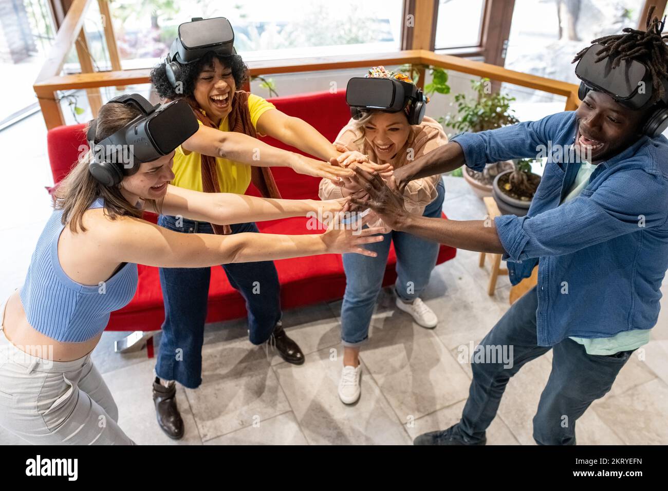 Groupe d'amis de l'âge et de l'ethnie mixte se préparent à jouer, le temps pour l'harmonie et le soutien mutuel avant le jeu virtuel, gagnant l'équipe mains vers le haut Banque D'Images