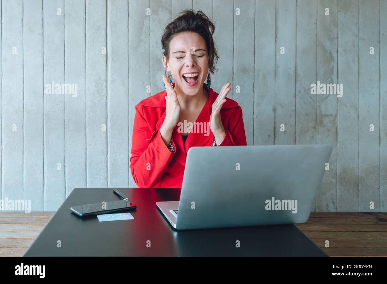 femme d'affaires caucasienne adulte avec son ordinateur portable criant avec joie pour son profit et la vente de ses produits en ligne, assis dans un restaurant travaillant Banque D'Images
