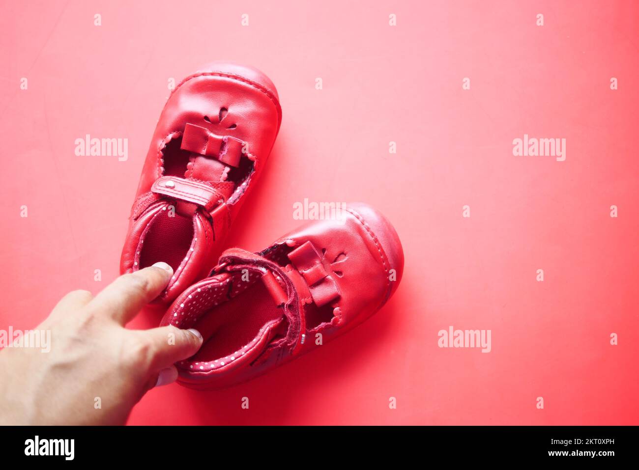 femmes portant des chaussures pour enfants sur fond rouge Banque D'Images