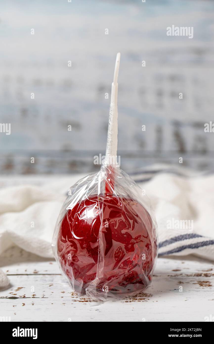 Bonbons aux pommes ou caramel rouge. Des pommes de bonbons au sirop sur fond de bois blanc. gros plan Banque D'Images