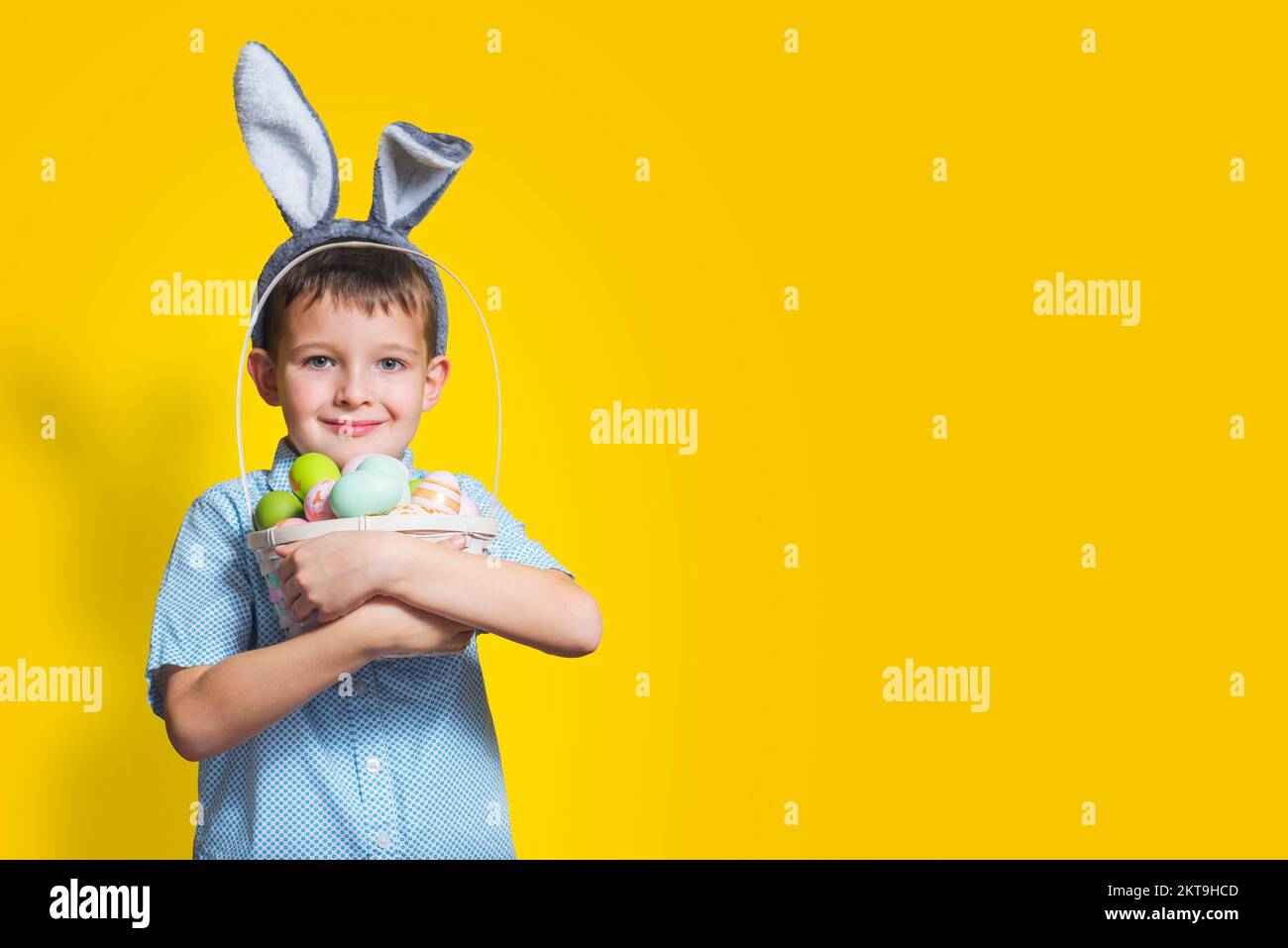 Enfant portant des oreilles de lapin le jour de Pâques et tenant le panier avec des œufs peints Banque D'Images