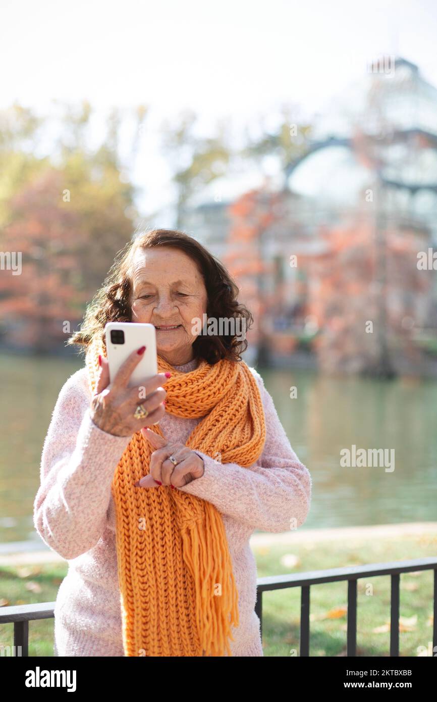 Femme âgée de race blanche utilisant un téléphone cellulaire à l'extérieur. Espace pour le texte. Banque D'Images