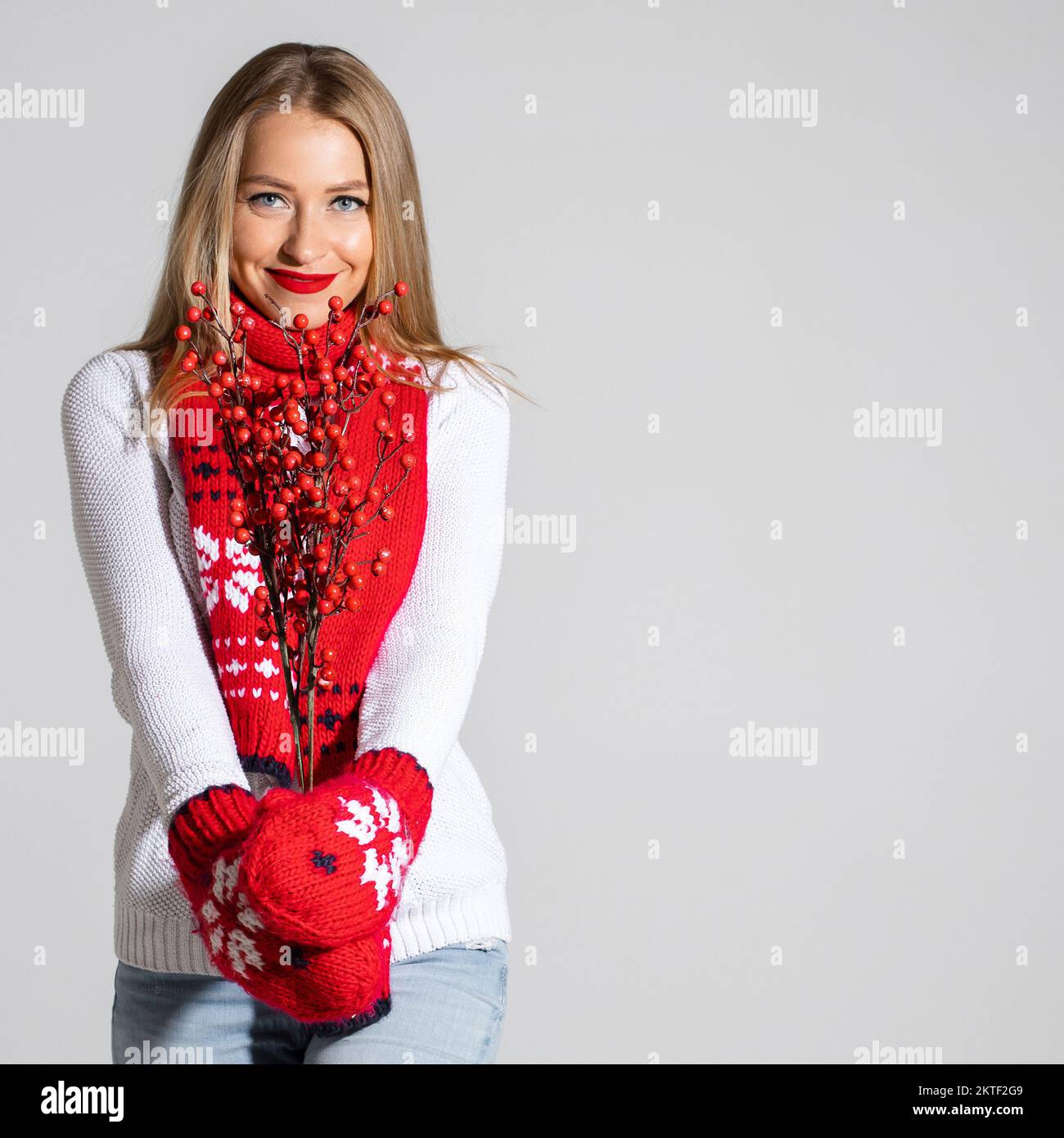 jolie femme en chandail blanc, foulard rouge et moufles rouges avec motif  de noël contient des fleurs rouges séchées Photo Stock - Alamy
