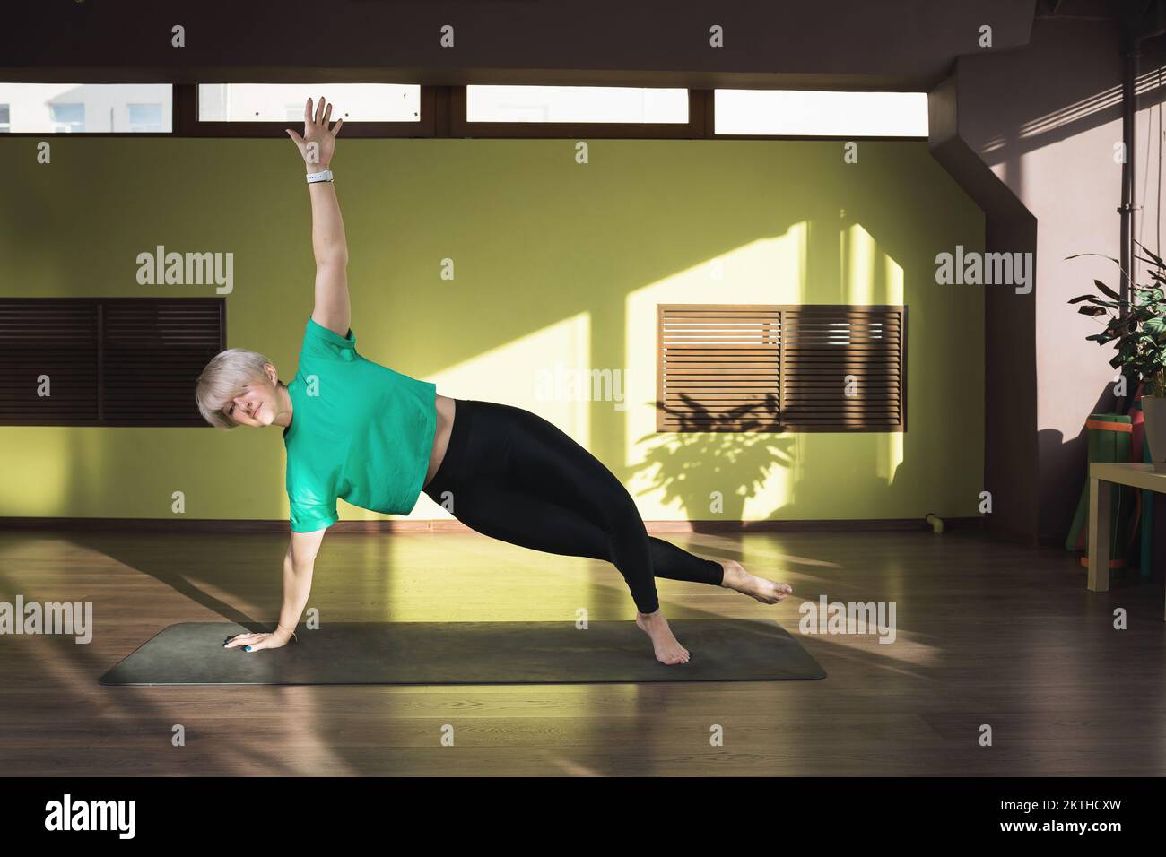 Une femme menant un mode de vie sain et pratiquant le yoga, exécute l'exercice wasishthasana, la posture d'une planche latérale, s'entraîne sur un tapis dans le goujon Banque D'Images