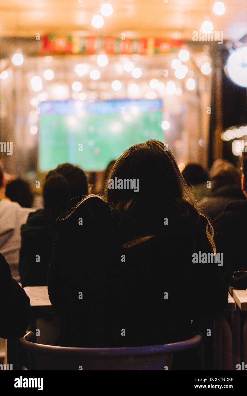 Des personnes non identifiables regardant un match de football la nuit dans un bar Banque D'Images