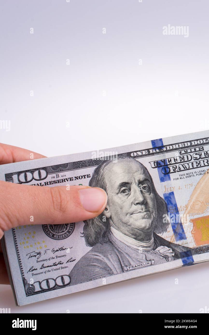 Human hand holding American dollar billets par le côté d'un modèle de maison sur fond blanc Banque D'Images