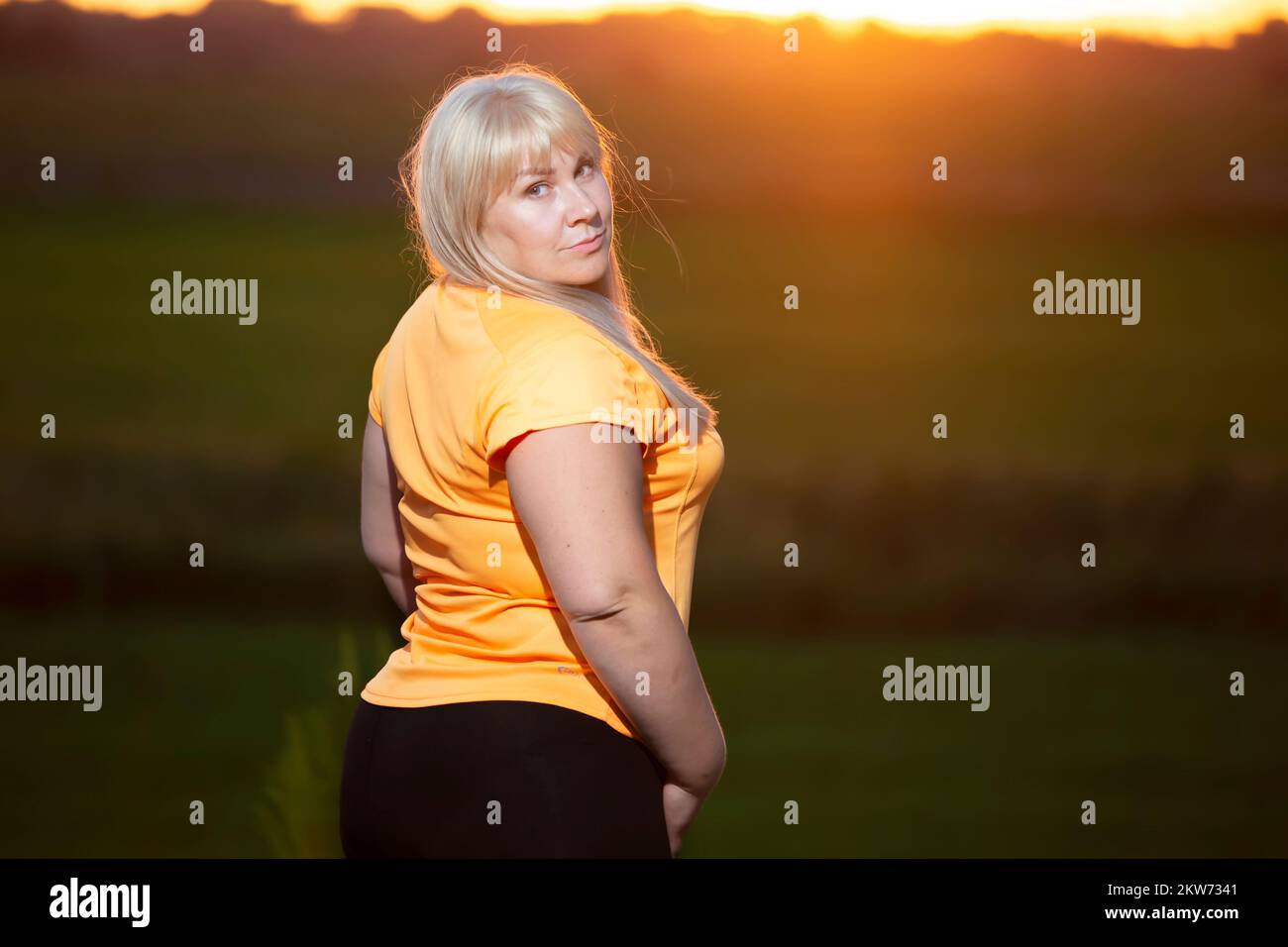 Portrait d'une femme européenne d'âge moyen dans un survêtement, posant pour l'appareil photo, relaxant. Femme excitée en surpoids dans un tracksuit tendance se reposant après e Banque D'Images
