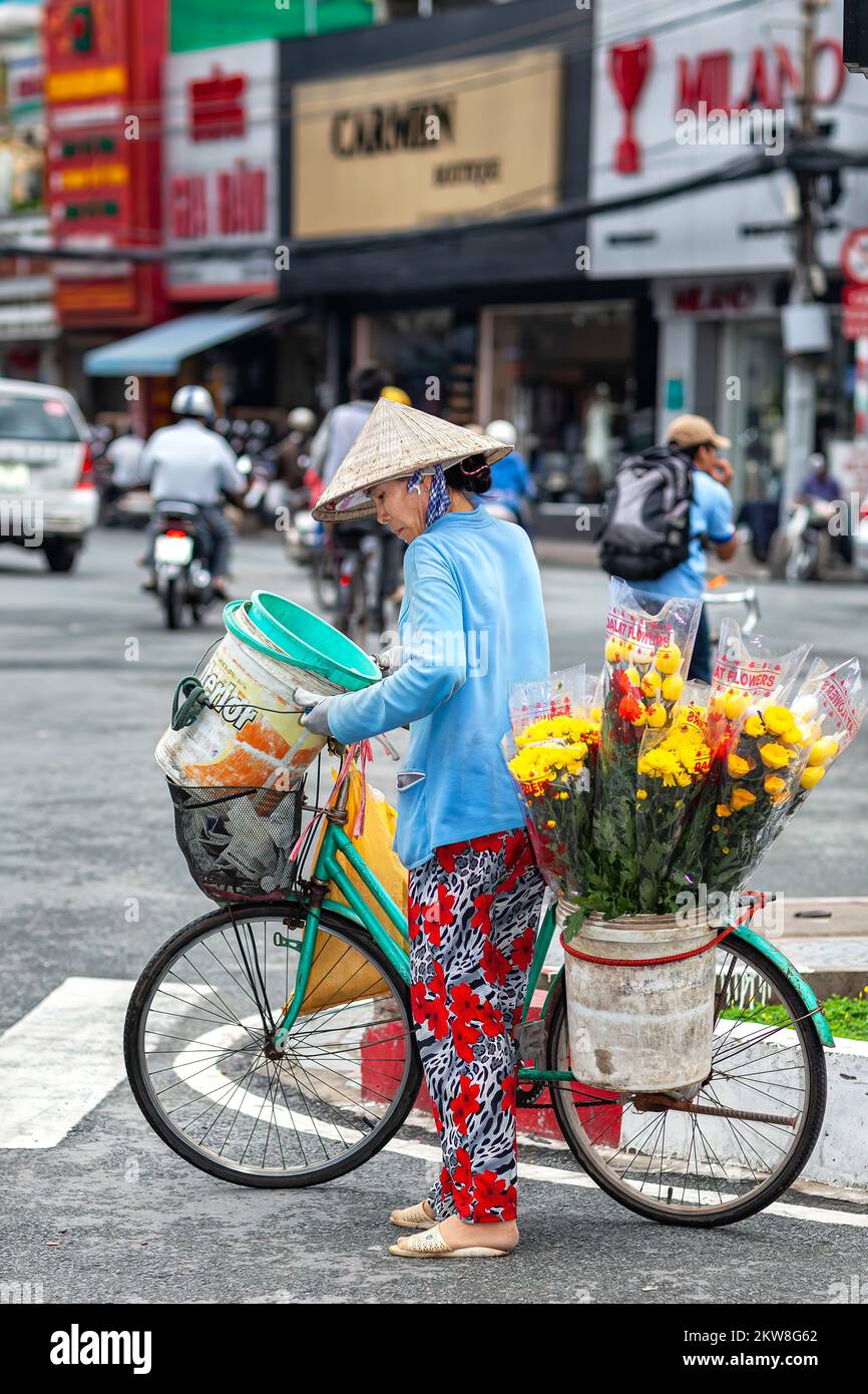 Femme vietnamienne vendeur portant un chapeau de bambou, avec vélo, Ho Chi Minh ville, Vietnam Banque D'Images