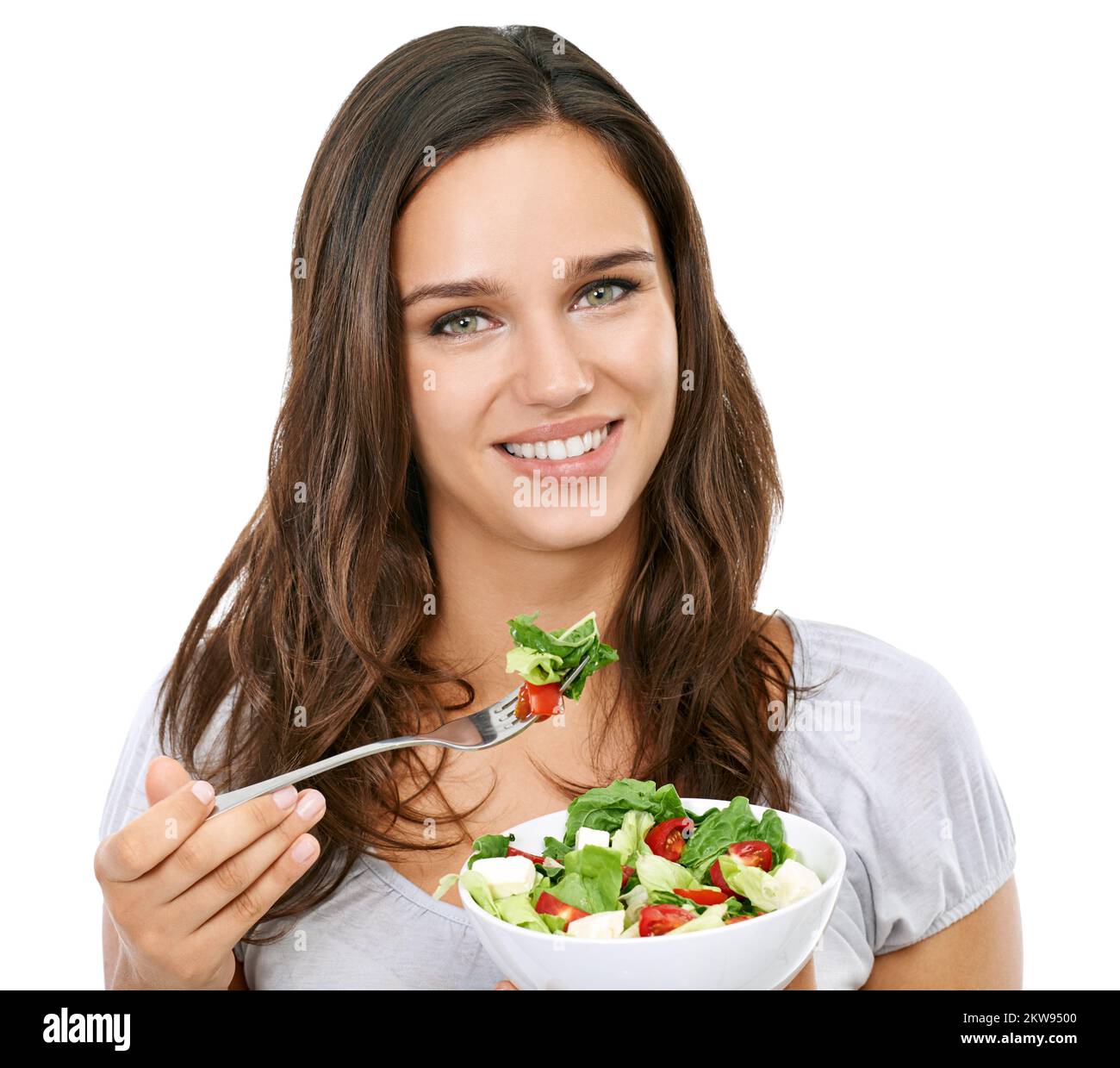 Un en-cas sain. Une belle jeune femme qui apprécie une salade fraîche isolée sur blanc. Banque D'Images
