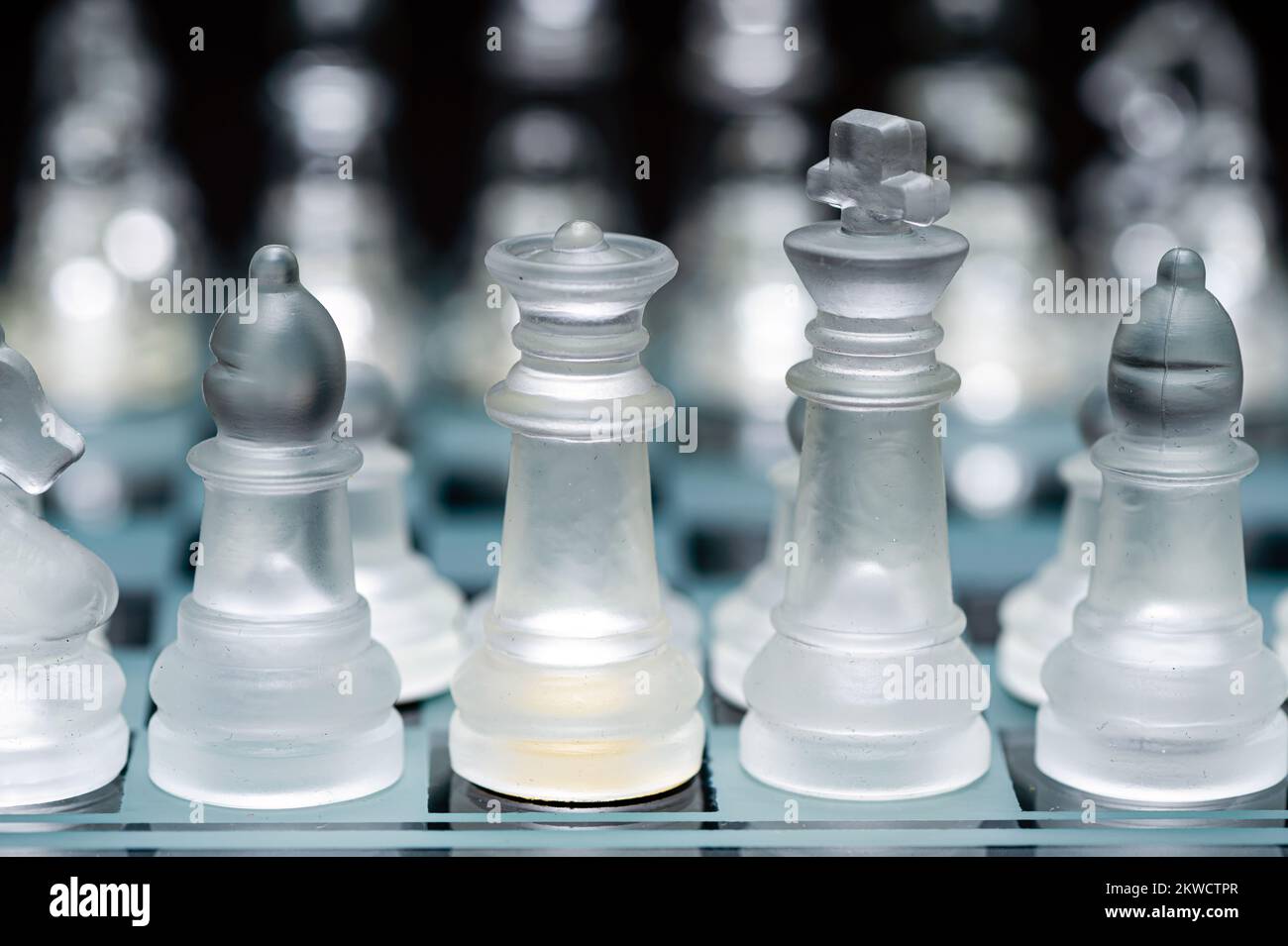 verre transparent, pièces d'échecs transparentes sur un damier, mise au point sélective, gros plan, isolé sur le noir Banque D'Images