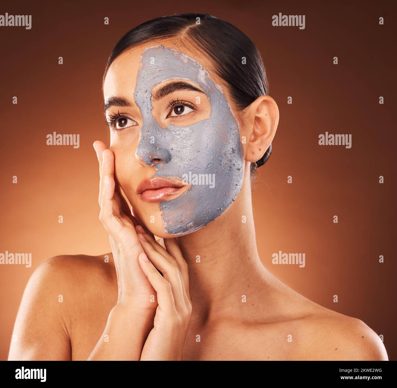 Femme, soin du visage et masque de boue sur fond orange en studio d'auto-soins, de dermatologie ou de traitement d'acné. Modèle de beauté, boue faciale et crème Banque D'Images