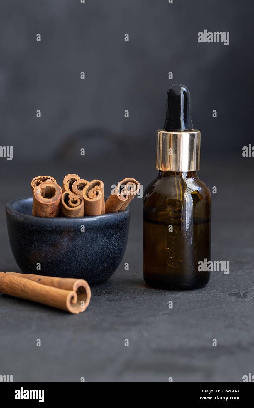 Huile essentielle de cannelle en bouteilles de verre et bâtonnets naturels de cannelle. Aromatherapy et Ayurveda concept. Banque D'Images