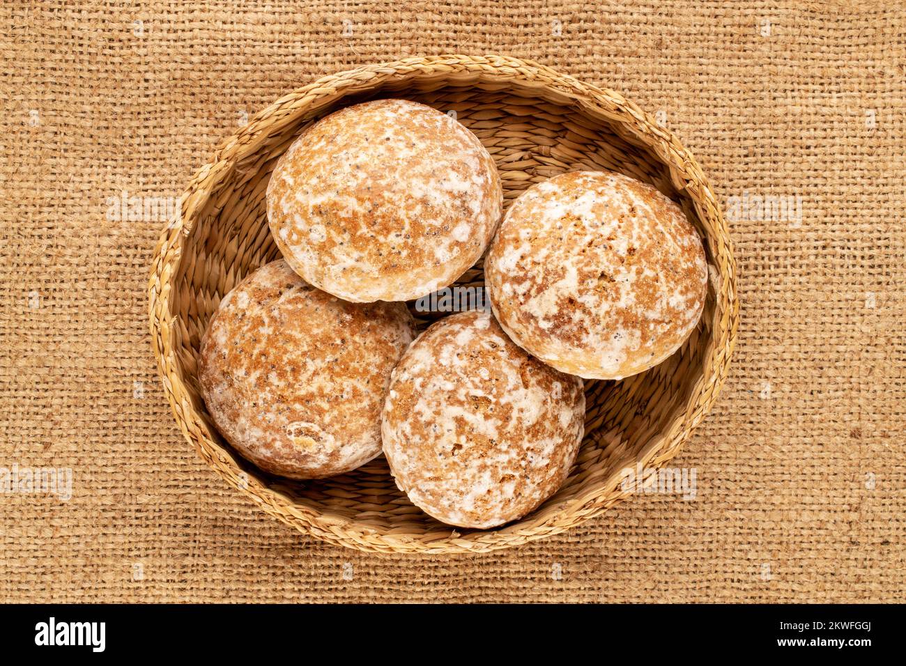 Plusieurs biscuits savoureux de pain d'épice doux dans une assiette de paille sur un jute tissu, macro, vue de dessus. Banque D'Images