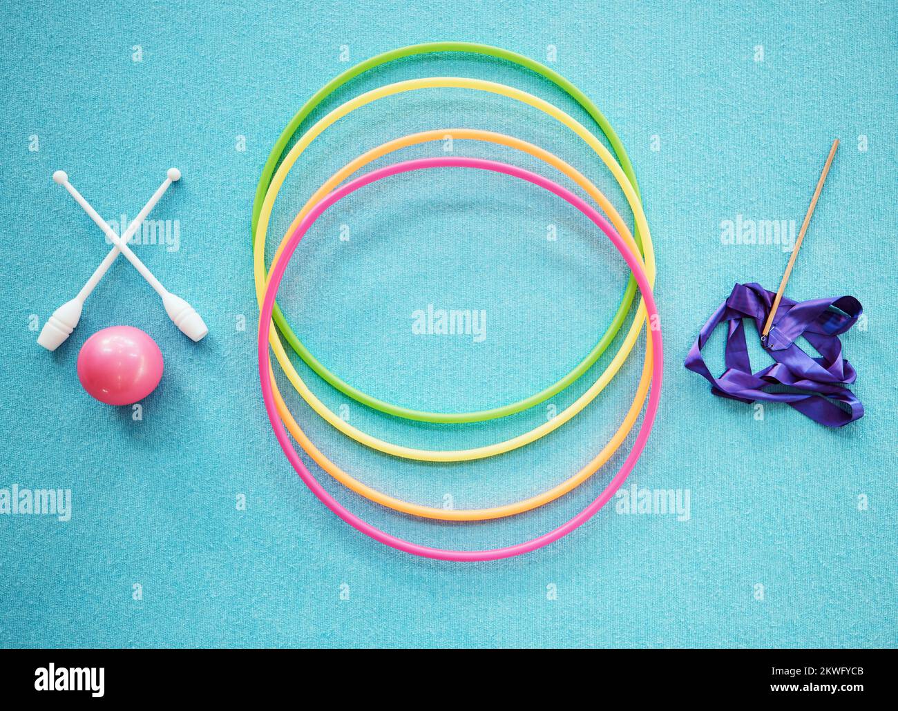 Gymnastique, danse et remise en forme avec un hula, un ruban et des barres sur un plancher bleu vide par le dessus pour l'exercice ou l'entraînement. Exercice, entraînement et Banque D'Images