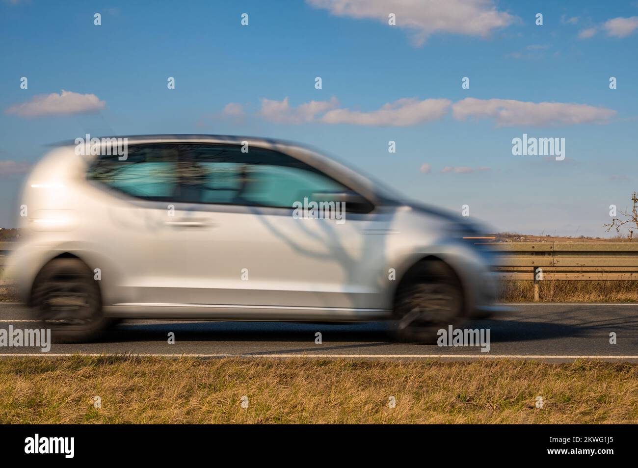 Les petites voitures font des courses sur la route de campagne contre le ciel bleu Banque D'Images