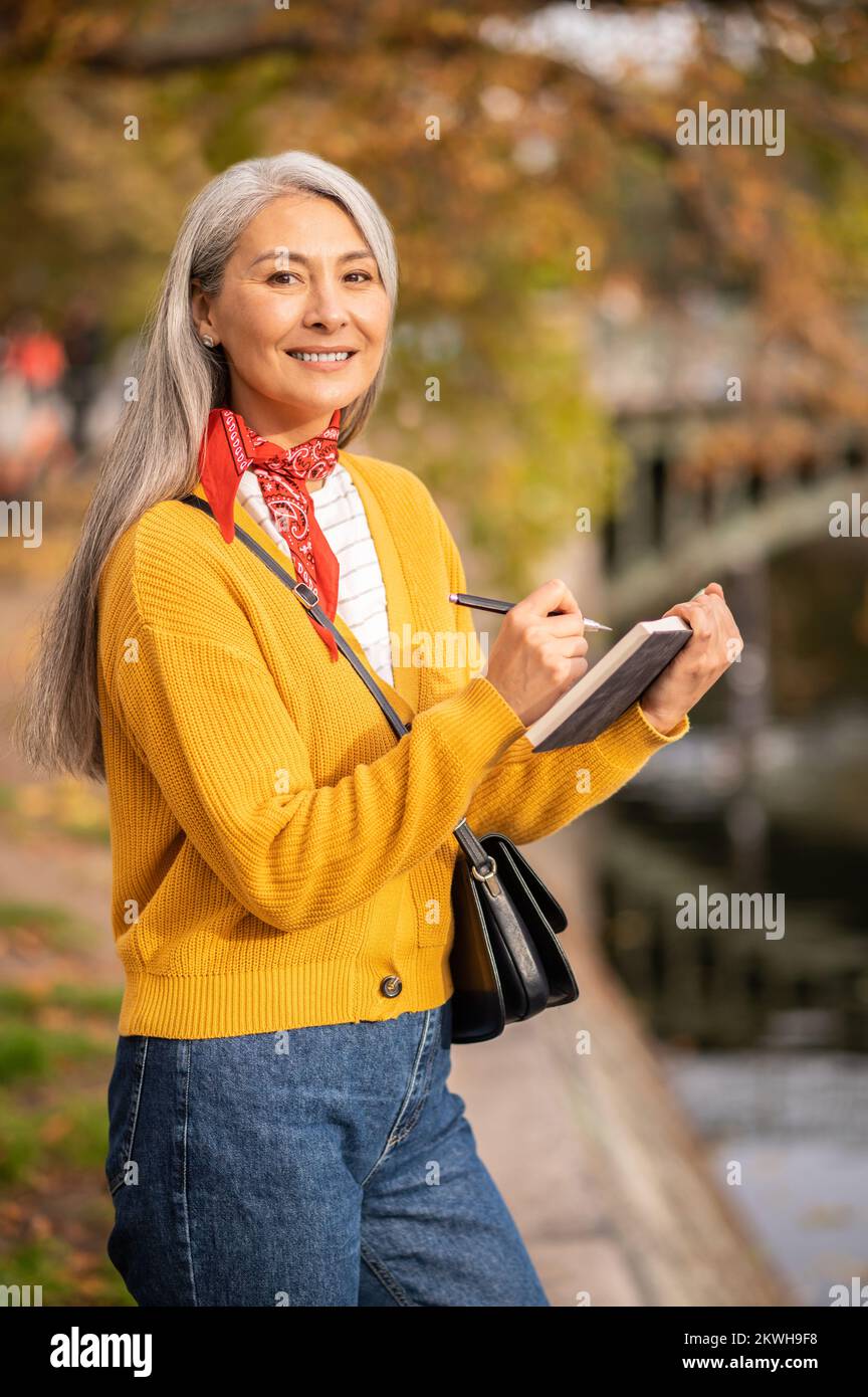 Femme inspirée avec un albom dans les mains sur la rive de la rivière Banque D'Images