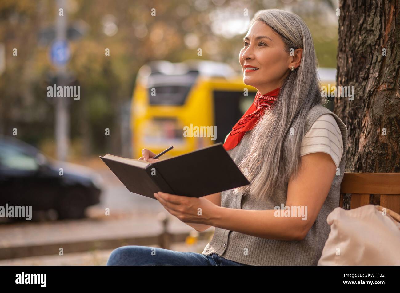 Jolie femme inspirée assise sur un banc dans le parc Banque D'Images