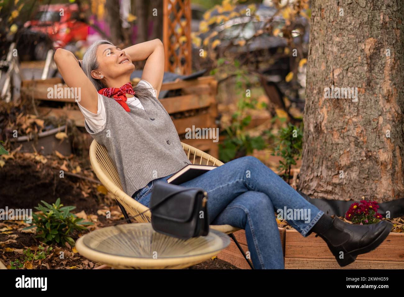 Une femme qui a l'air bien assise sur le banc dans le parc et qui a l'air détendue Banque D'Images