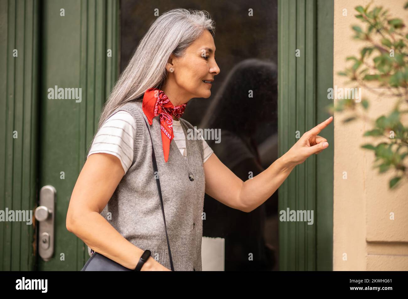Femme debout à l'entrée de la maison et pressérant le code d'accès Banque D'Images